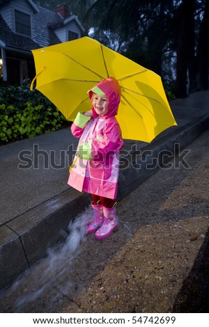 Little Girl With Yellow Umbrella Playing In Rain Wearing Pink Rain ...