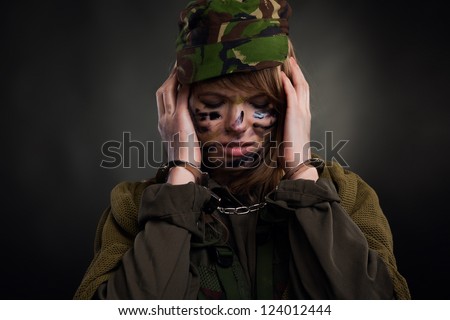 army girl cover ears with hands in handcuffs closed eyes, soldier woman in a military uniform over black background