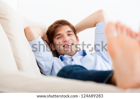 Man lying down on sofa happy smile looking at camera dreaming resting