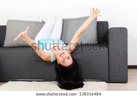 young woman excited smile lying relaxing on the couch, sofa home indoors, happy girl raised up arms hands reached out palm at you looking at camera