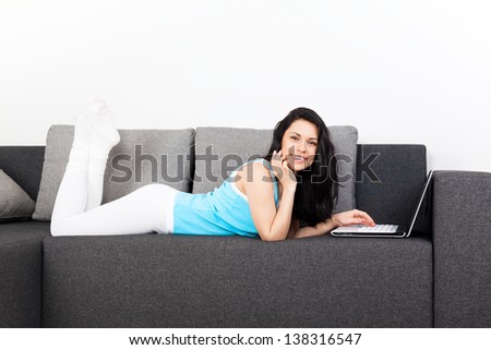 woman happy smile with laptop lying on sofa at home, young beautiful girl surfing on computer