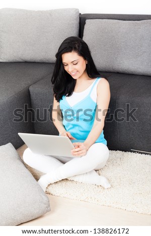 woman happy smile with laptop sitting on floor near sofa at home, young beautiful girl surfing on computer