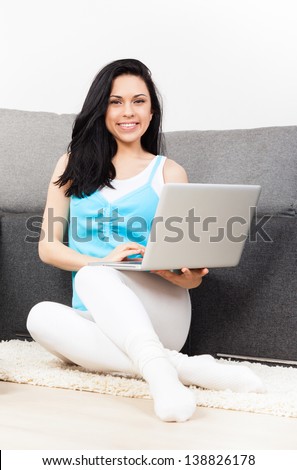 woman happy smile with laptop sitting on floor near sofa at home, young beautiful girl surfing on computer