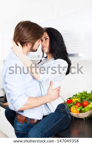 couple sensual kissing at their kitchen home, young romantic family date man embrace and kiss woman