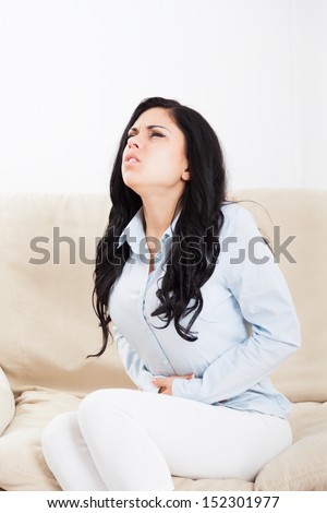 stomach ache, sick woman hold hand on stomach pain, young girl sitting on sofa at home