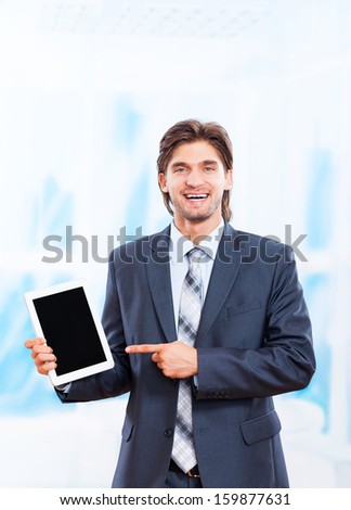 business man happy smile hold tablet pad computer point finger to empty touch screen with copy space in bright blue office, young businessman smiling