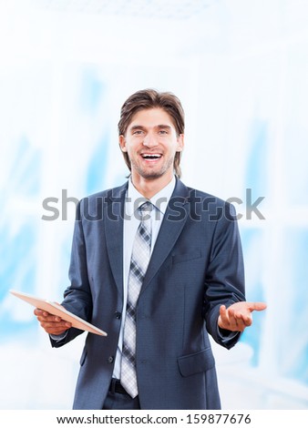 business man happy smile hold tablet pad computer in bright blue office, young businessman smiling hand gesture