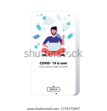 man taking off face mask guy sitting lotus pose using laptop victory over coronavirus pandemic quarantine covid-19 is ending concept smartphone screen mobile app copy space full length vector