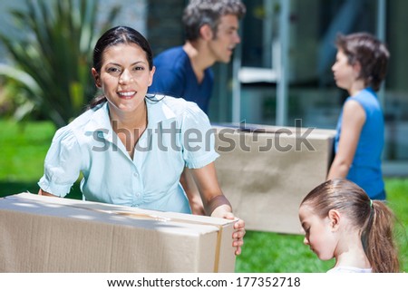 family moving into a new house, happy parents with two children carrying box smile