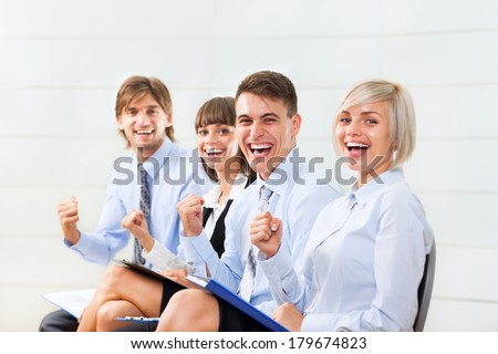 Successful excited Business people group team, young businesspeople smile hold fist ok yes gesture sitting in row line at office desk