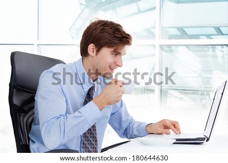 businessman drink coffee or tea hold cup sitting at desk in office using laptop computer, handsome young business man happy smile