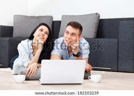 couple dream, think using laptop, drink coffee hold cup, lying on floor near couch, sofa looking up to copy space happy smile, young man and woman