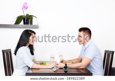 Young couple sitting at table holding hands, romantic dinner date