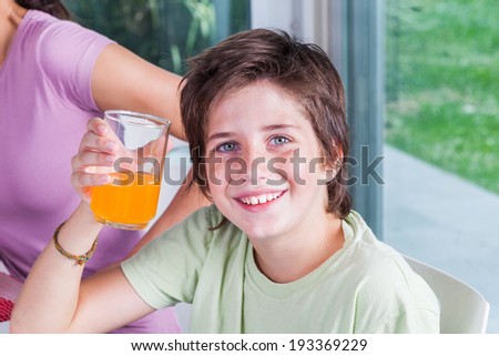 little boy drink orange juice happy smile, sitting at table lunch restaurant or cafe
