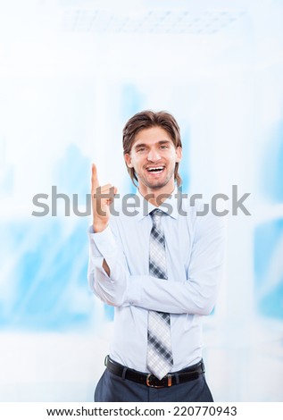 Handsome young business man happy smile point finger to empty copy space, businessman showing pointing up, concept of idea over blue office background
