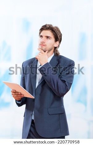 young business man think look up hold tablet pc computer, in bright blue office, businessman executive wear suit pondering