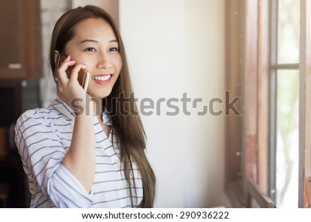 Asian woman cell phone call smile talking near window