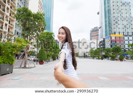 Asian woman holding man hand happy smile leads walk city street
