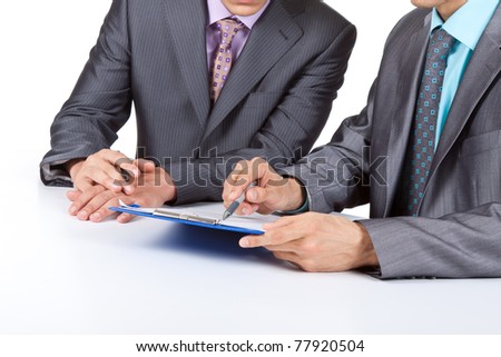 Two business people in elegant suits sitting at desk working in team together and discussing the problem holding clipboard, folder with papers, document, business plan. Isolated over white background.