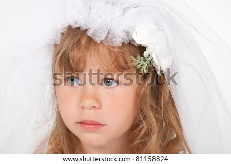 close up portrait of adorable little girl in a wedding dress the bride, pout sad after crying looking nervously 4 years child with brunette curly long hair, veil brides on head over white background.