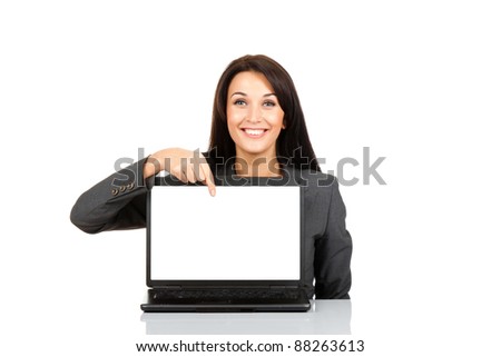 beautiful business woman smile sitting at the desk looking at camera, point finger at isolated white laptop screen over white background