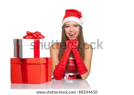 Happy excited christmas santa girl smile looking at camera sitting at the table with gift box, isolated on white background