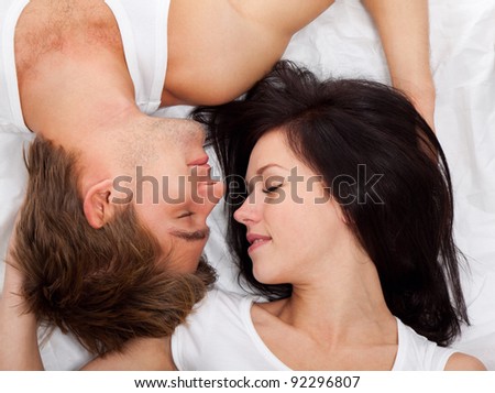 young lovely happy couple lying in a bed, sleep with closed eyes, top view.