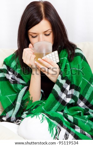 Ill woman covered with blanket drink tea, hold cup and pack of pills, sitting at home on sofa couch