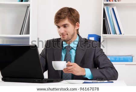 businessman drink coffee or tea hold cup sitting at desk in office using laptop computer, handsome young business man happy smile