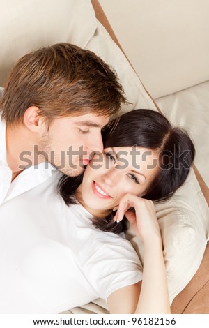 beautiful young happy couple  laying on couch happy smile, young lovely man kiss woman, romantic love embrace on the sofa, top angle view