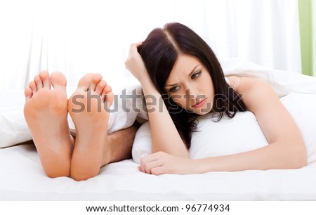 young upset couple lying in a bed, having conflict problem. sad woman face on pillow negative emotions concept and man feet