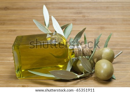 A bottle of olive oil lying on some olives.