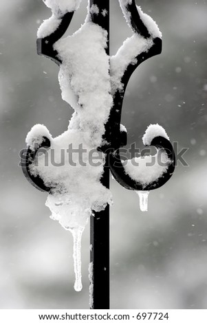 Snow and ice on a wrought iron railing in the middle of a winter snowstorm.