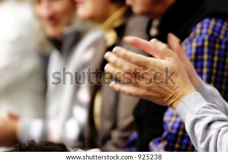 Blurred motion image (slow shutter speed) of a pair of hands clapping in a crowd.