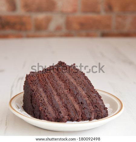 A piece of chocolate fudge cake on a brick wall background, selective focus