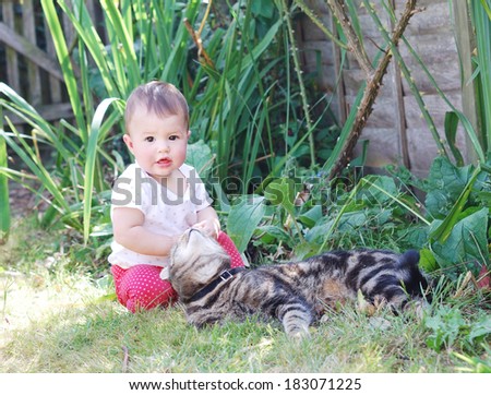 Little baby playing with a cat in the garden