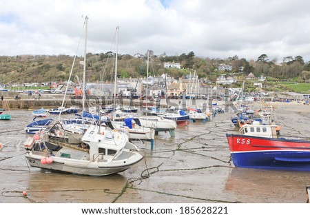 LYME REGIS, ENGLAND - APRIL 08: Boats in low tide, Lyme Regis harbour, Jurassic Coast, Dorset, England, April 08, 2012. The town is famous for the fossils found in the cliffs and beaches.