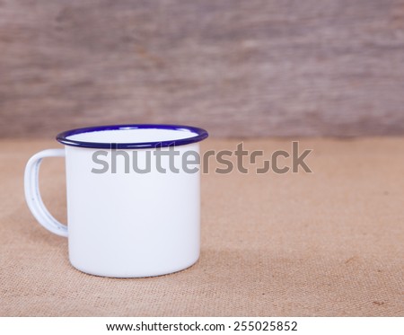 Empty white and blue enamel mug on the table, selective focus
