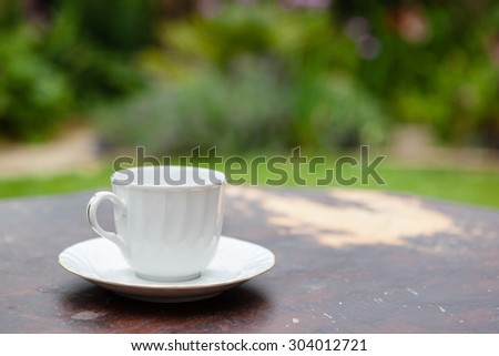 Empty white cup on the wooden table in the garden