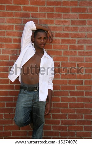African American Man Leaning Against  a Grungy Brick Wall With Chest Exposed