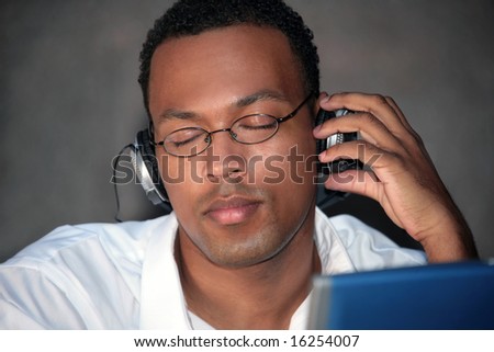 African American Male Listening to Music With Headphones on His Laptop Computer