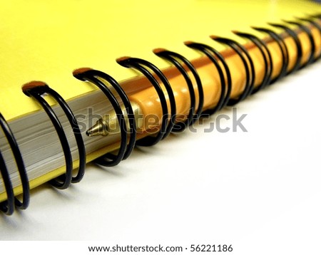 Yellow spiral ring bound notebook with ballpoint pen inside the spiral