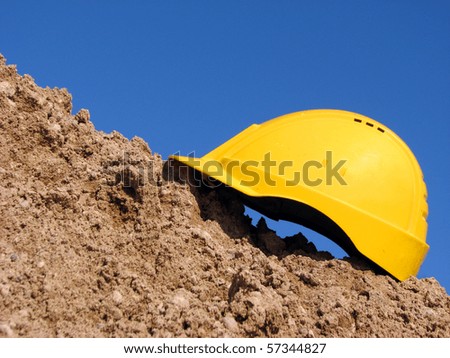 Yellow hard hat on the sandpile against the blue sky