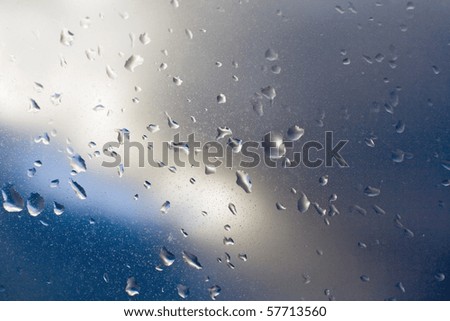 Raindrops on window against cloudy sky
