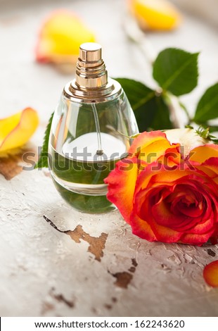 perfume bottle and red yellow rose on the old desk