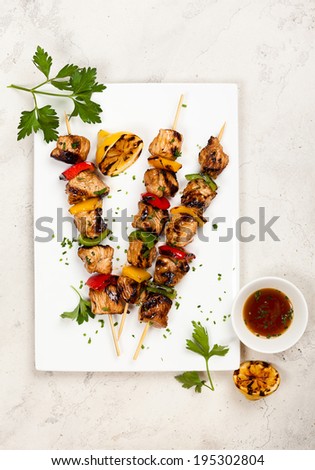 Grilled meat and vegetable kebabs on the white plate