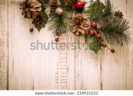 Christmas background with fir branches,pinecones and berries on the old wooden board