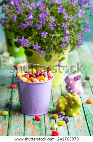 Easter rabbits and bucket with jelly beans on the vintage wooden table