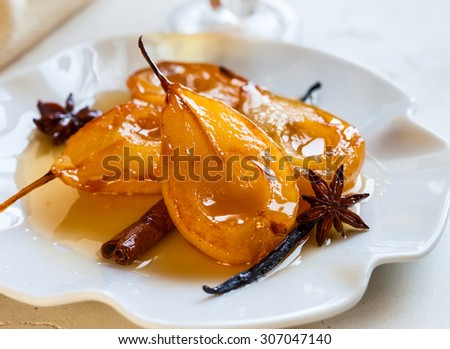 Poached pears with spices in syrup on the white plate. Delicious dessert for holiday