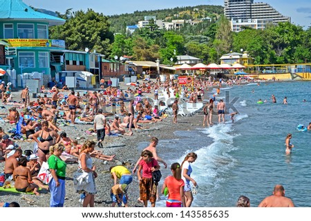 ALUSHTA, UKRAINE - JUN 01: People on the public pebble beach near Black Sea in Alushta, Ukraine on June 01, 2013. Alushta is famous Crimean resort. More 6,134 mln. tourists visited Crimea in 2012.